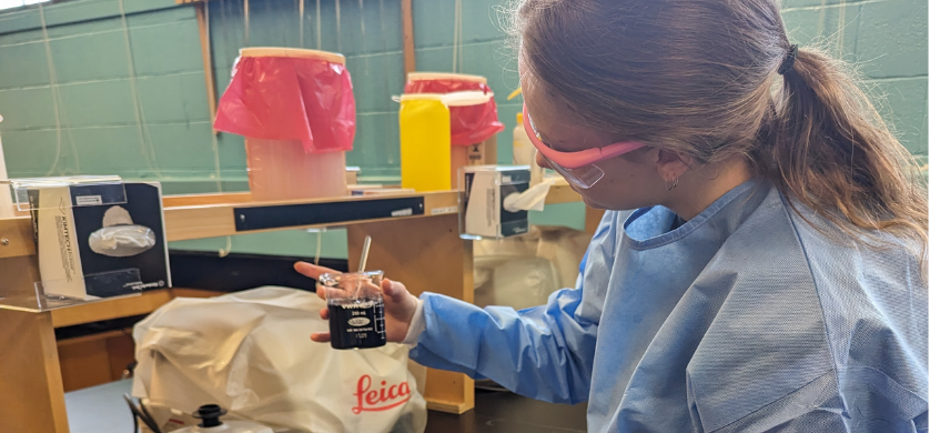 A student in protective gear working in a lab